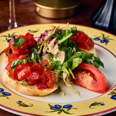 Bruschetta topped with tomatoes and mixed greens.