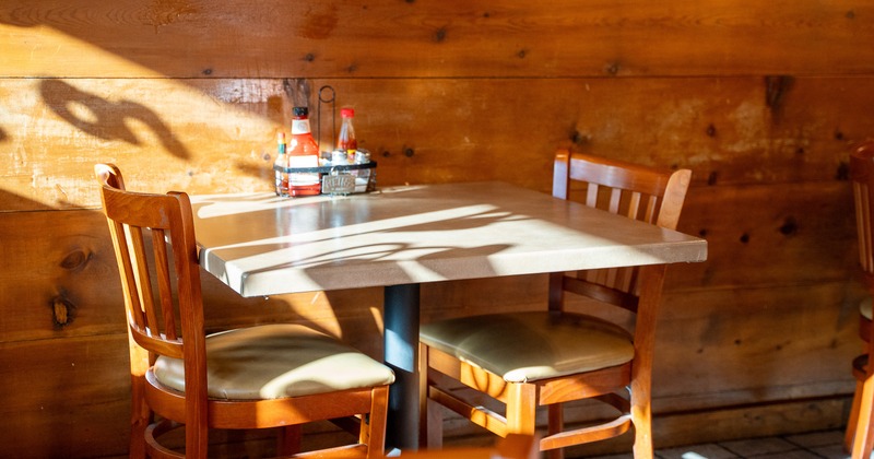 Wooden dining table for two guests by the wall