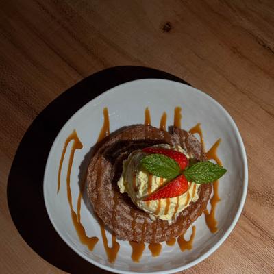 A churro dessert topped with ice cream scoop.