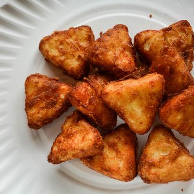 Several pieces of cheese curds on a white plate, top view.