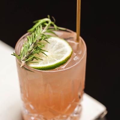 Cocktail with mezcal, cranberry coulis, lime juice, and rosemary.