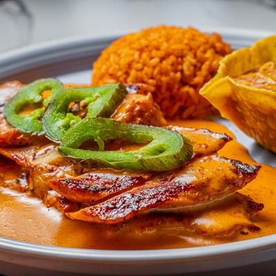 Grilled chicken breast served with rice and beans.