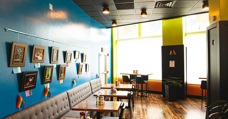Interior, banquette seating with tables and chairs by a wall decorated with pictures