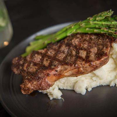 Grilled New York Strip steak, on a bed of mashed potatoes, with asparagus.
