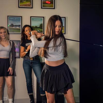 A guest is captured mid-swing with a golf club in golf simulator enclosure.