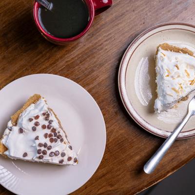 Two pieces of pie served on the table with cup of coffee, top view.
