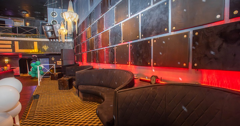 Nightclub with curved dark seating booths, patterned carpeting, and red accent lighting