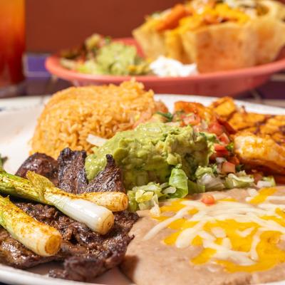 Combo plate of grilled chicken breast, skirt steak, and shrimp served with sides.