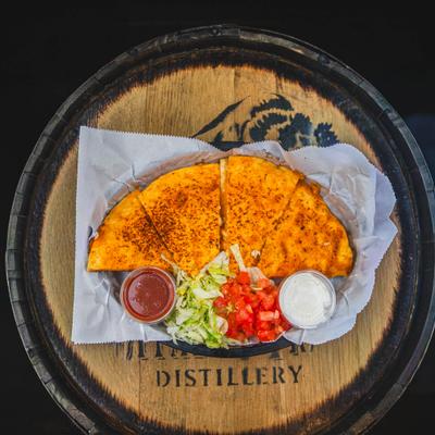 Quesdilla served with shreded lettyce, diced tomato and two dipping sauces, overhead view.