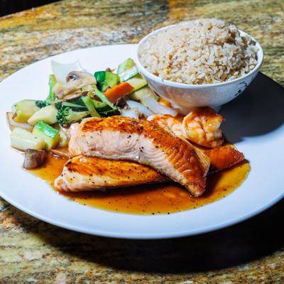 Grilled salmon fillet with sauteed vegetables and brown rice.