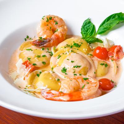 Ravioli and shrimp in a creamy sauce, garnished with parsley, cherry tomatoes and cheese slices, close up