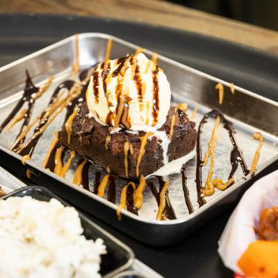 Brownie topped with ice cream and drizzle of sauces.