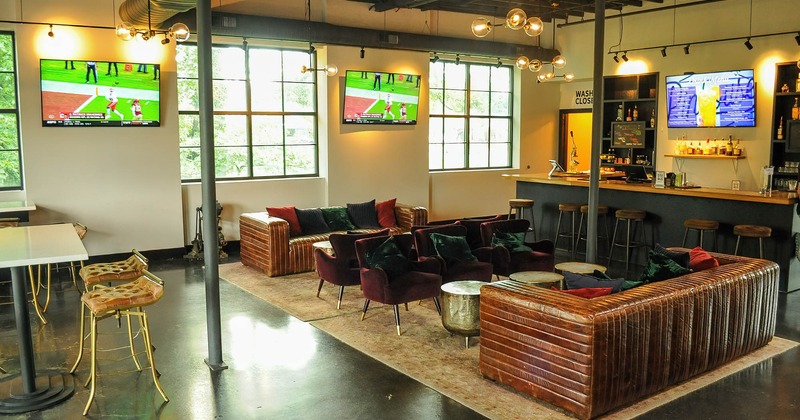 Interior, cozy seating area bear the bar, TV screens on the wall