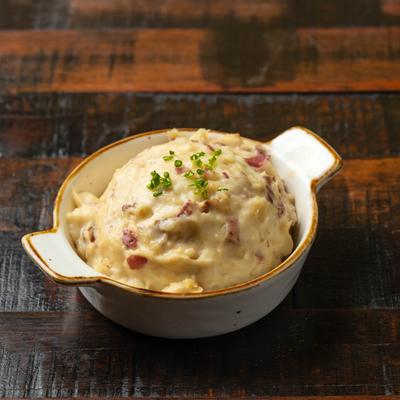 A bowl of Mashed Potato with Brown Gravy placed on a rustic wooden table.