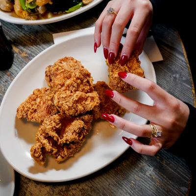 Hands grabbing fried chicken.