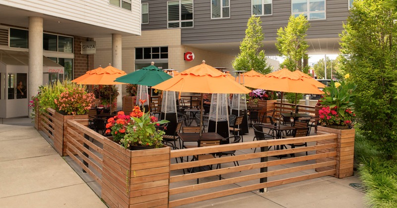 Exterior, partially covered seating area, tables under colorful parasols, plants