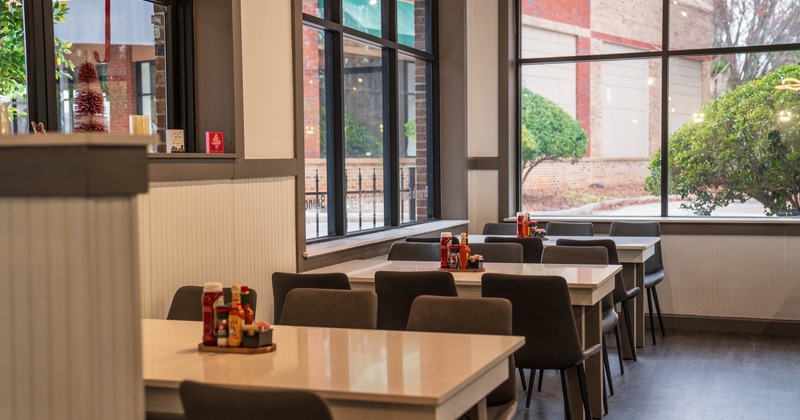 Restaurant interior with tables and chairs near large windows