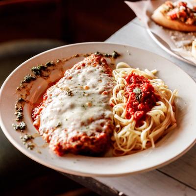 Chicken Parmigiana alongside spaghetti with tomato sauce.