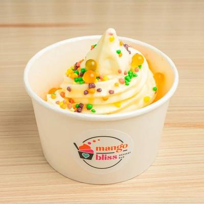 Cup of frozen yogurt topped with colorful sprinkles and candy pieces.