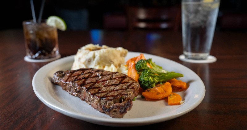 New York steak with baked potato and steamed vegetables
