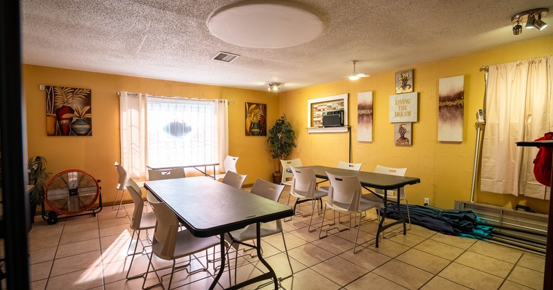 Room with tables, chairs, art on yellow walls