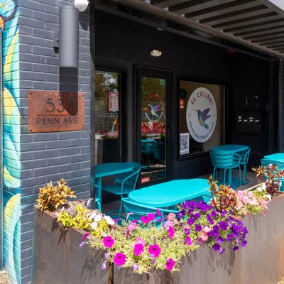 Restaurant entrance with outdoor seating and colorful flowers.