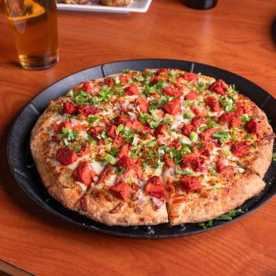 Tandoori Chicken Pizza alongside a glass of beer.