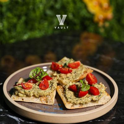 Small, thin slices of toasted bread topped with a spread, cherry tomatoes, and herbs.