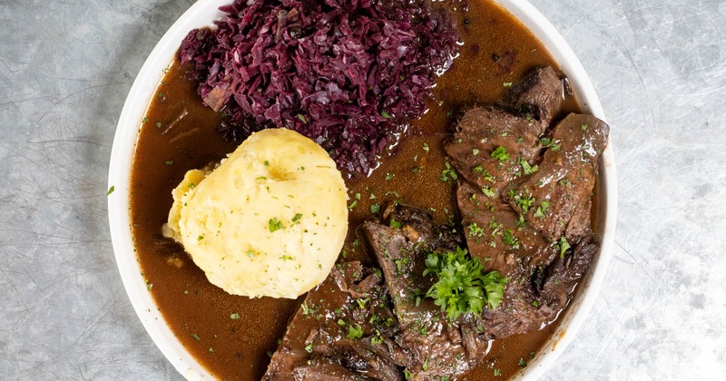Beef brisket in gravy with red cabage and potato dumplings, overhead view