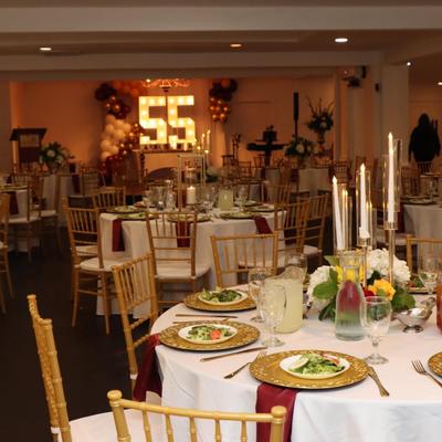 Banquet tables with served appetizers, lit candles and an illuminated number display centerpiece.