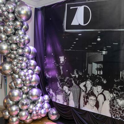 Silver balloon column by a black and white event backdrop.