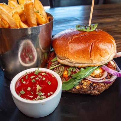 Burger served alongside a small container of French fries and a dipping sauce.