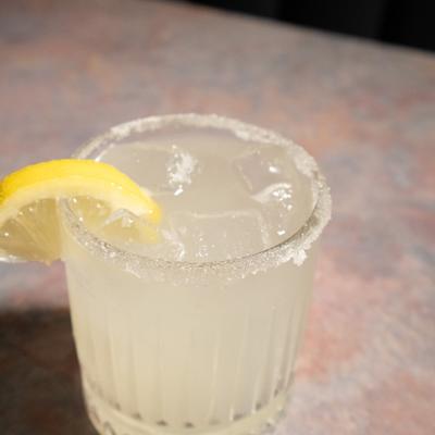 Lemon Drop cocktail in sugar-rimmed glass, garnished with lemon slice.