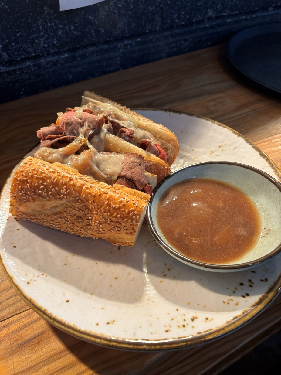 French Onion Soup Gratinée - Rich, caramelized onions simmered in savory beef broth, topped with crusty bread and a generous layer of melted Gruyère.
- WITH - 
Wagyu French Onion Soup French Dip - Slow-roasted Wagyu beef, thinly sliced and piled onto a crusty roll with SP sauce, caramelized onions, and Gruyère. Served with rich onion soup for dipping.  
*Available Everyday*