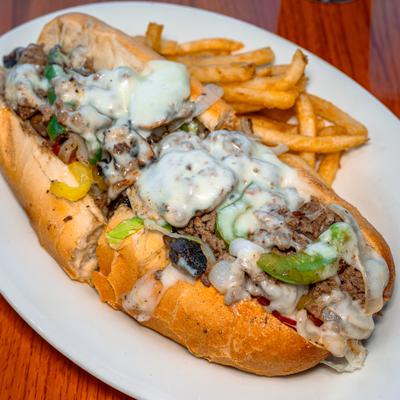 Philly cheesesteak sandwich with melted cheese, peppers, onions, and crispy french fries.