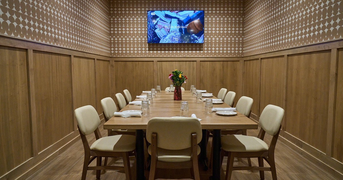 Private room, a table set with tableware and chairs, with a TV screen on a wall