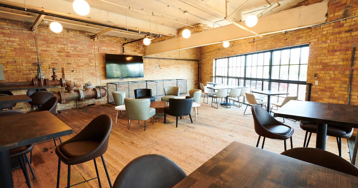 Lounge seating area with tables, chairs, and large windows