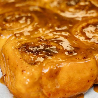 Glazed cinnamon roll covered in caramel icing.