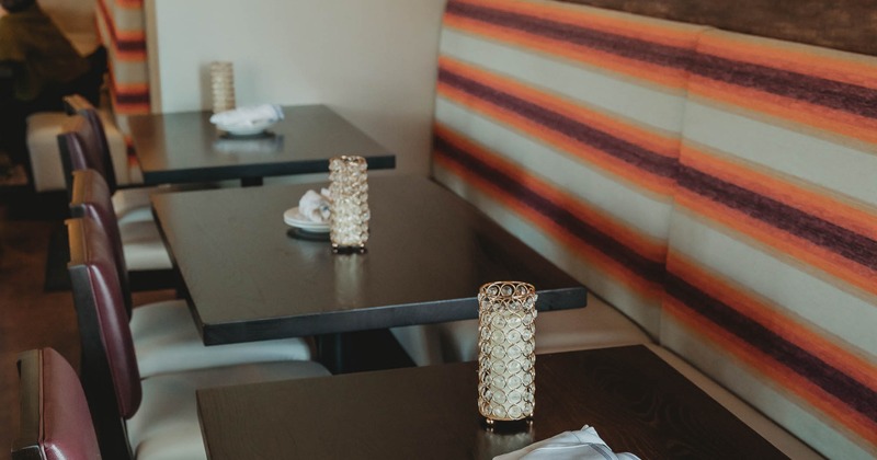 Restaurant interior with dark wooden tables, striped bench seating