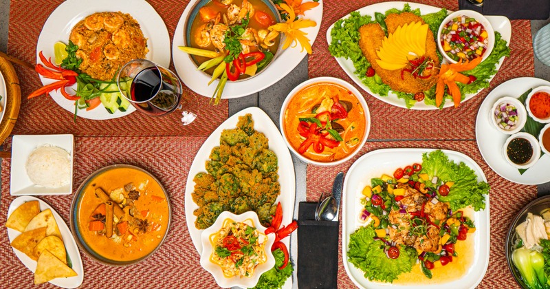 Assortmen of Thai dishes served alongside a glass of red wine