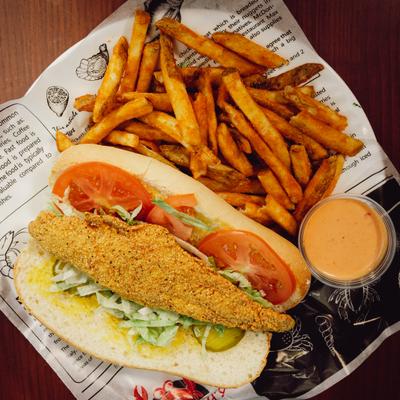 Fried catfish po' boy sandwich with fries and dipping sauce.