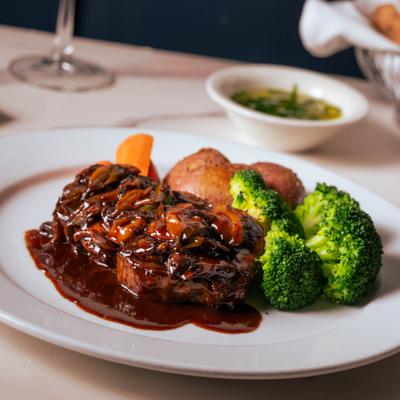 Filet mignon covered in port wine reduction sauce with mushrooms, served with broccoli and potatoes.