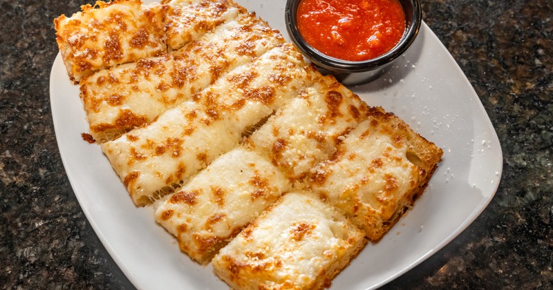 Cheesy garlic breadsticks served with a side of marinara sauce