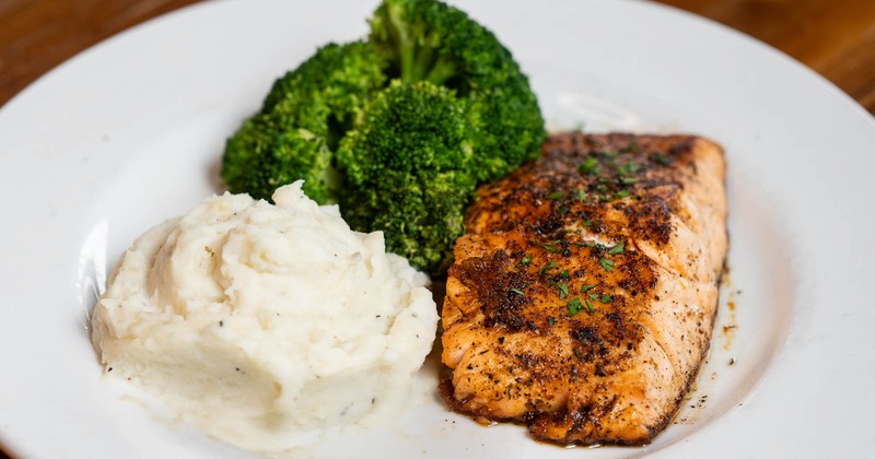A white plate holds grilled salmon, mashed potatoes, and broccoli