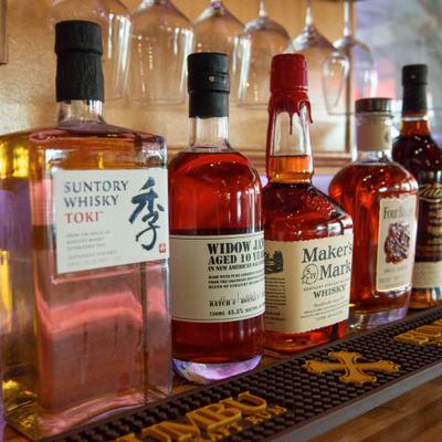 Assorted whiskey bottles lined on a bar shelf.