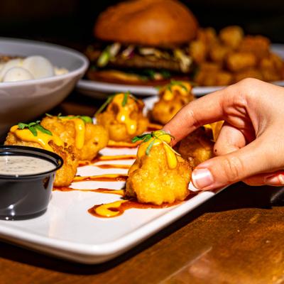 Hand taking a bite of Buffalo cauliflower from the plate.