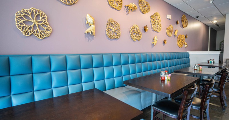 Interior, blue leather banquette seating and tables by a wall decorated with filigree shapes