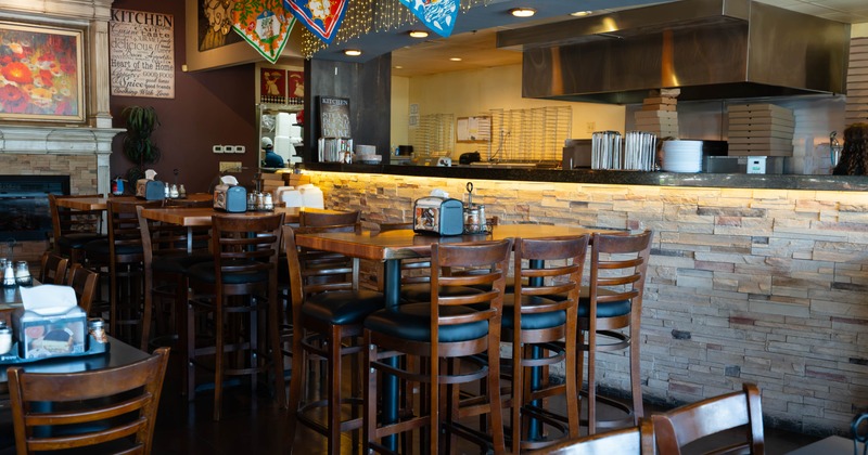 Interior, wooden tables and chairs, colorful banners, and a dark granite bar area