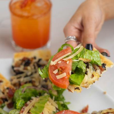 Flatbread with smoked bacon, lettuce, tomato, black olives, onions, and parmesan.