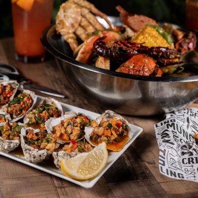 Seafood boil served on a table with plate of steamed oysters and a cocktail.